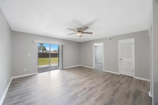 a view of an empty room with a window and wooden floor