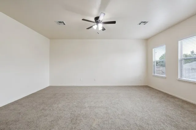 an empty room with a ceiling fan and window