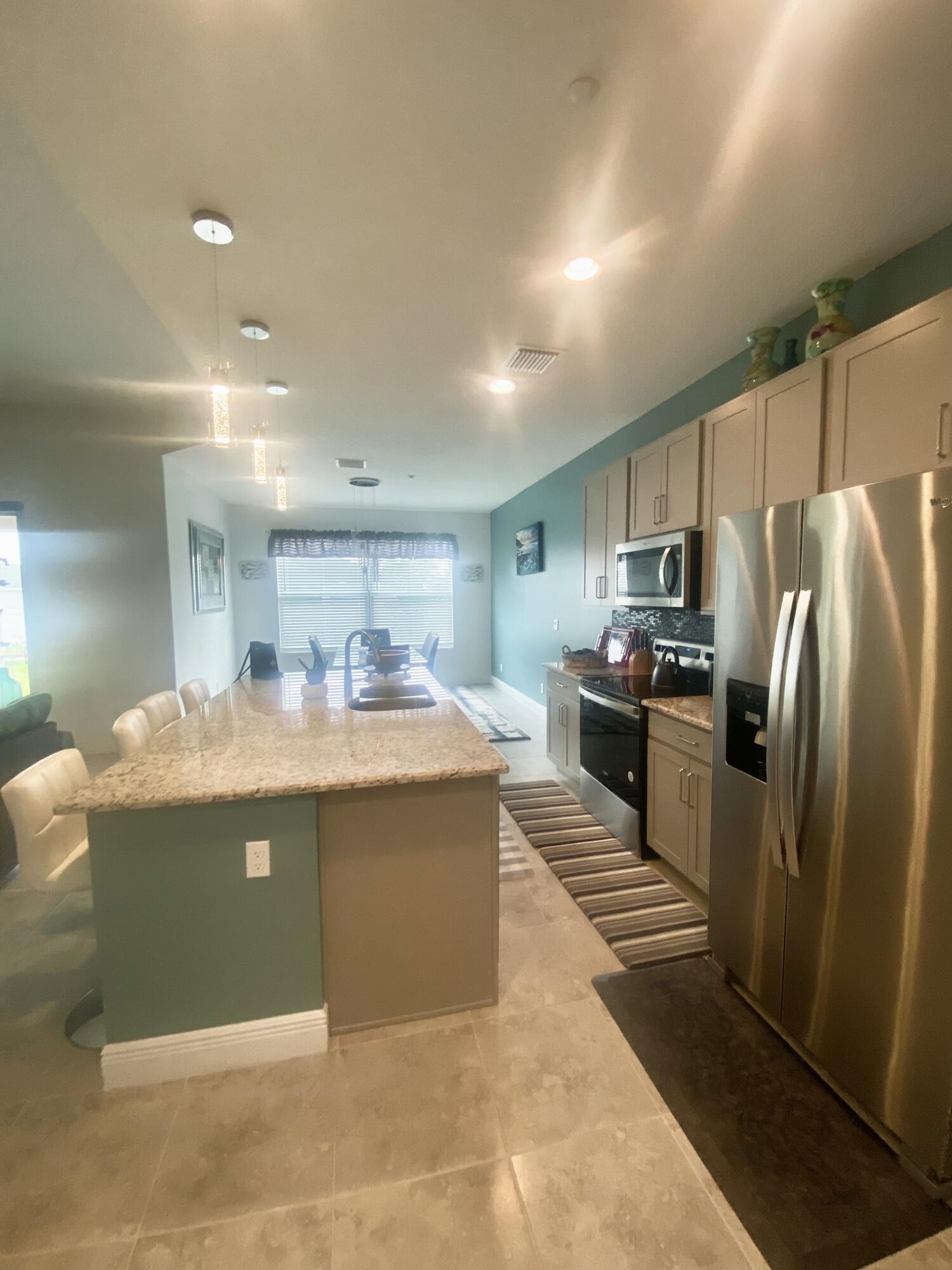 656 Southwest Haas Avenue Port St. Lucie, FL 34953 - Photo 12 of 31 a kitchen with stainless steel appliances granite countertop a sink and refrigerator