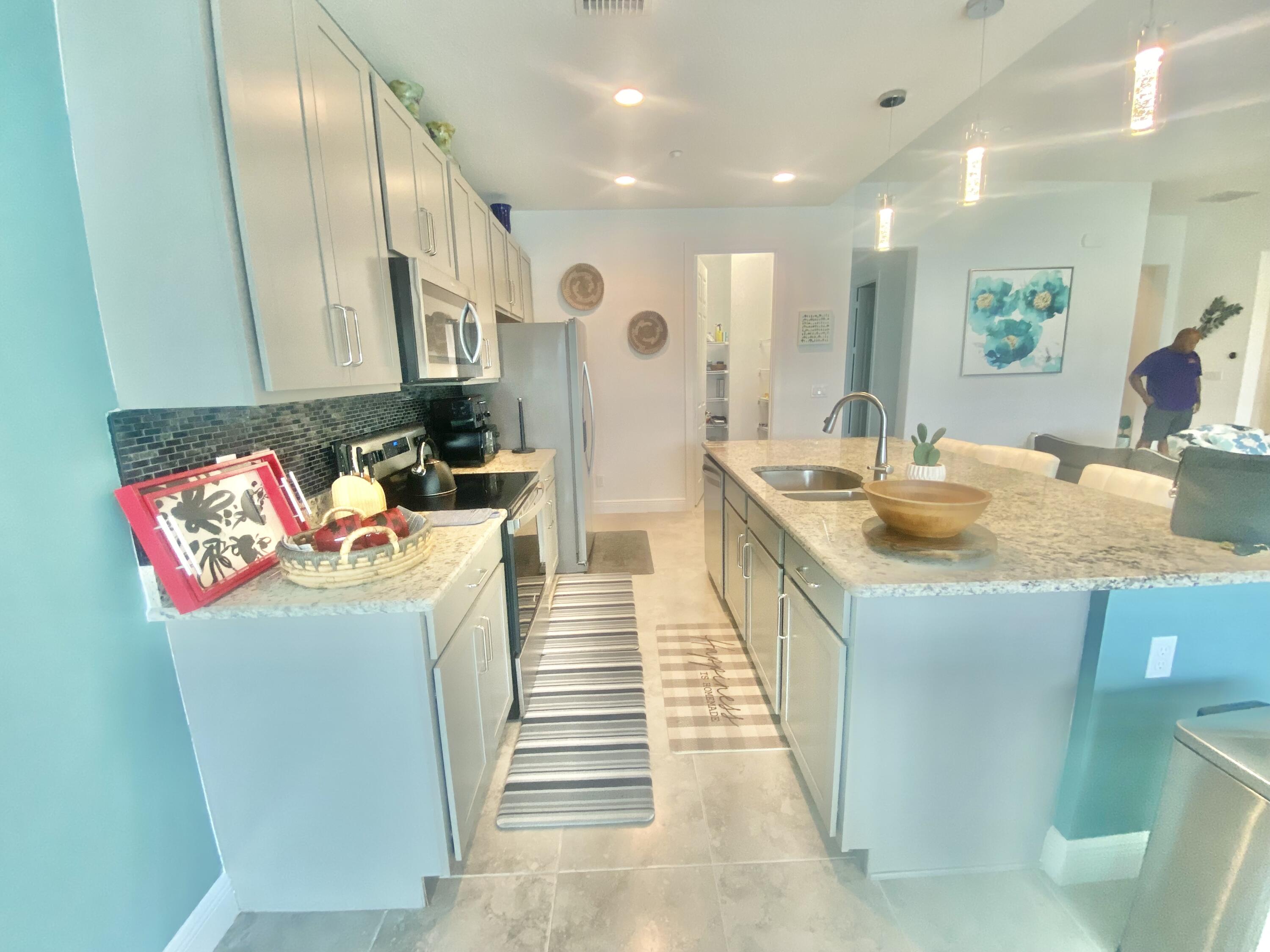 656 Southwest Haas Avenue Port St. Lucie, FL 34953 - Photo 10 of 31 a kitchen with kitchen island granite countertop a sink and refrigerator