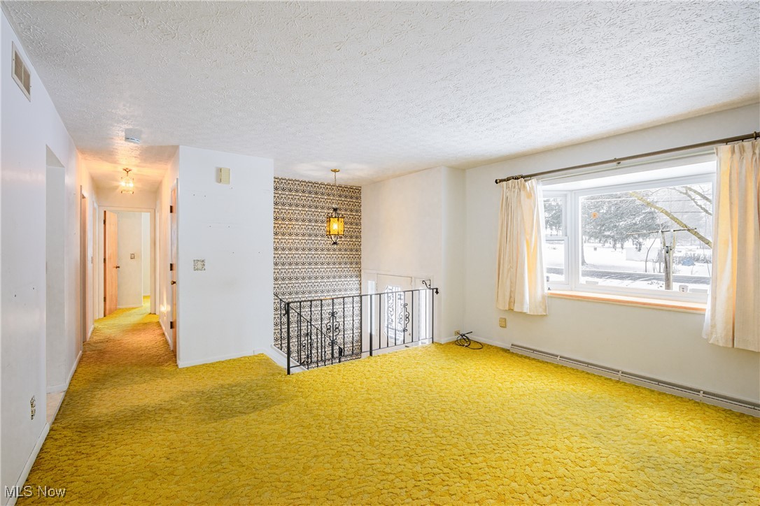 5905 Renninger Road New Franklin, OH 44319 - Photo 5 of 31 Spare room featuring carpet, a baseboard radiator, and a textured ceiling