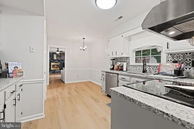 a kitchen with stainless steel appliances granite countertop a sink dishwasher and cabinets with wooden floor