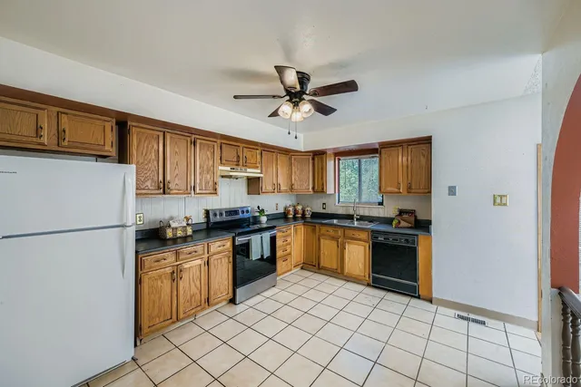 a kitchen with granite countertop a refrigerator stove top oven and sink