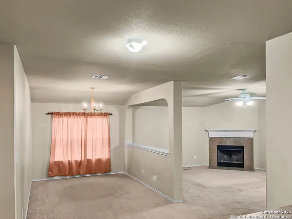 an empty room with windows fireplace and fans