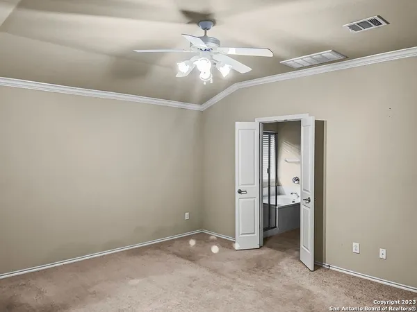 an empty room with a bathroom and a chandelier fan