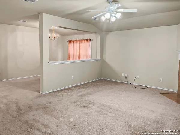 an empty room with a chandelier fan and windows