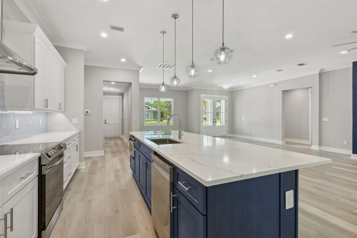 96050 Captains Pointe Road Yulee, FL 32097 - Photo 10 of 37 a kitchen with a stove center island a sink cabinets and wooden floor