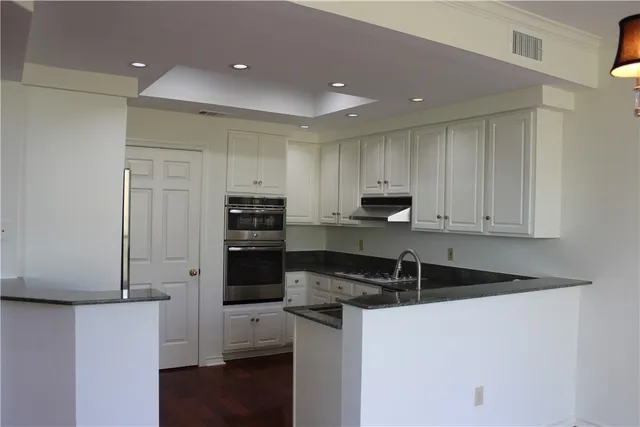 a kitchen with stainless steel appliances granite countertop a refrigerator and a stove top oven