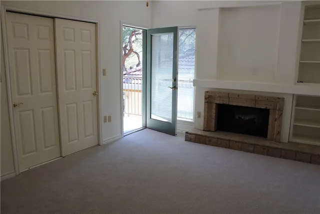 an empty room with windows and fireplace