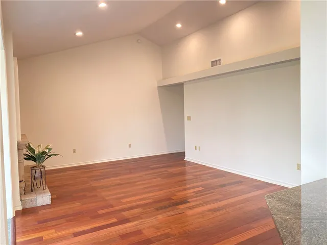 an empty room with wooden floor and potted plant
