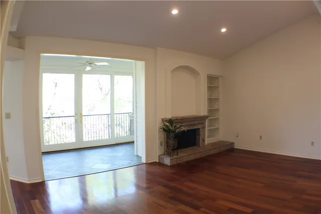an empty room with wooden floor and fireplace