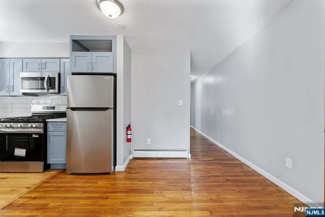 a view of a kitchen with refrigerator and wooden floor