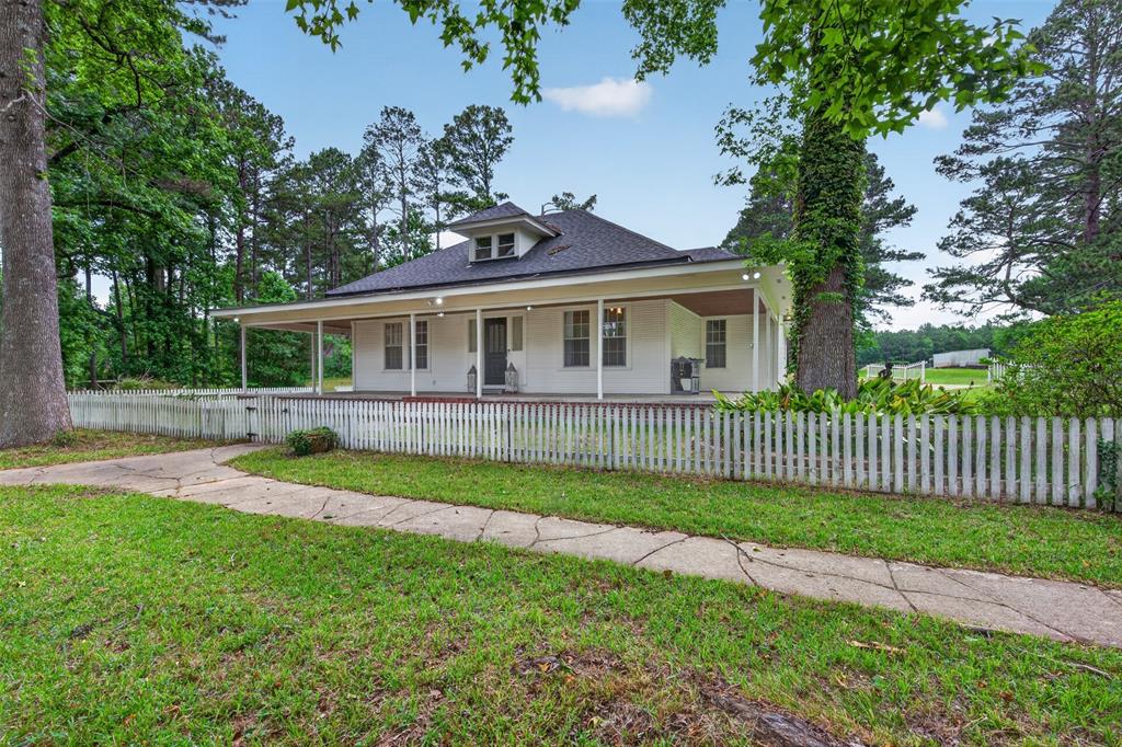 a view of a house with a yard and a large tree