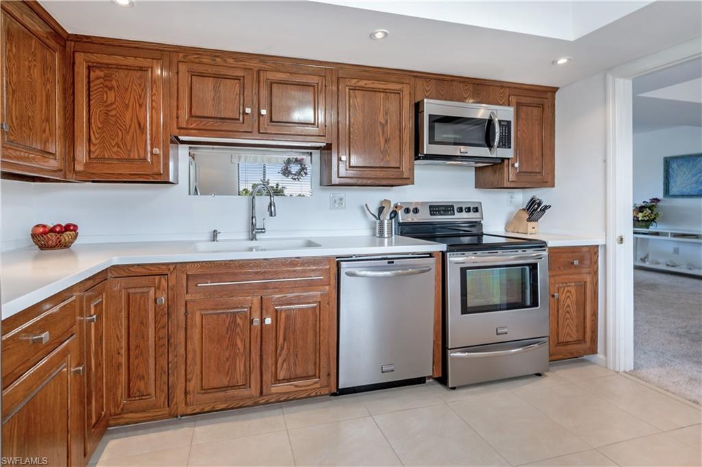 415 Augusta Boulevard, Unit 307 Naples, FL 34113 - Photo 13 of 36 a kitchen with stainless steel appliances granite countertop a sink stove and microwave