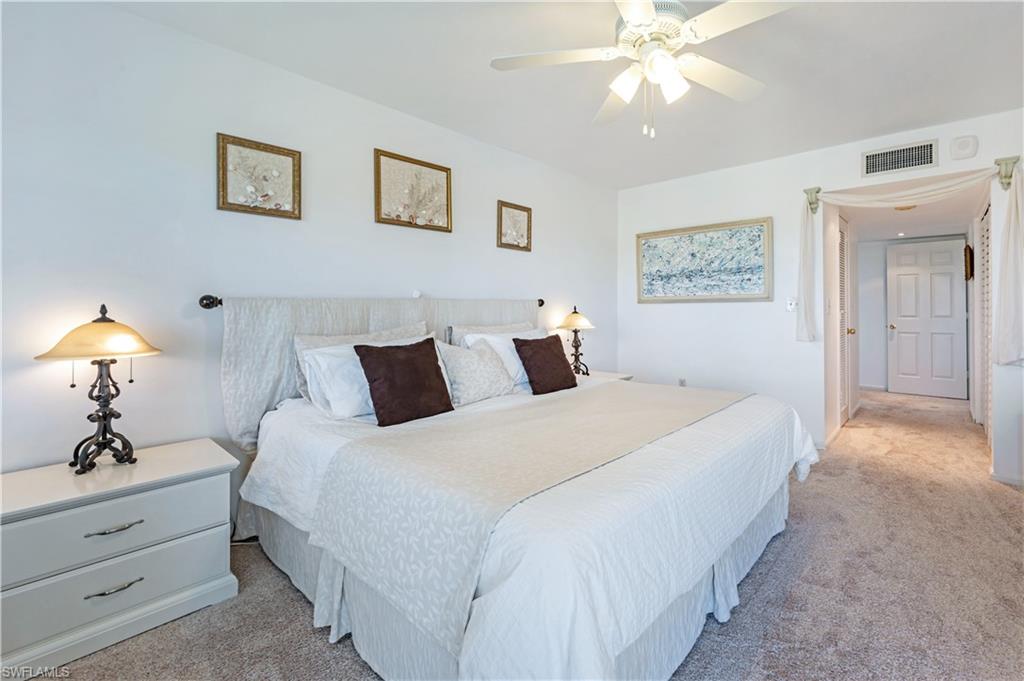 415 Augusta Boulevard, Unit 307 Naples, FL 34113 - Photo 23 of 36 a spacious bedroom with a bed and a chandelier