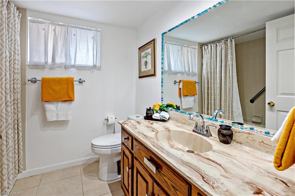 415 Augusta Boulevard, Unit 307 Naples, FL 34113 - Photo 25 of 36 a bathroom with a sink a toilet and mirror