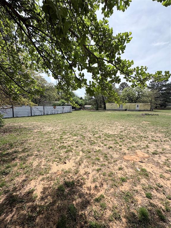 6295 Rendon New Hope Road Fort Worth, TX 76140 - Photo 34 of 38 Expansive outdoor area featuring a large grassy expanse, mature trees providing natural shade, and a distant structure with a light-colored exterior