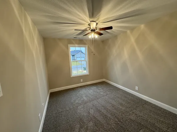 an empty room with windows and fan