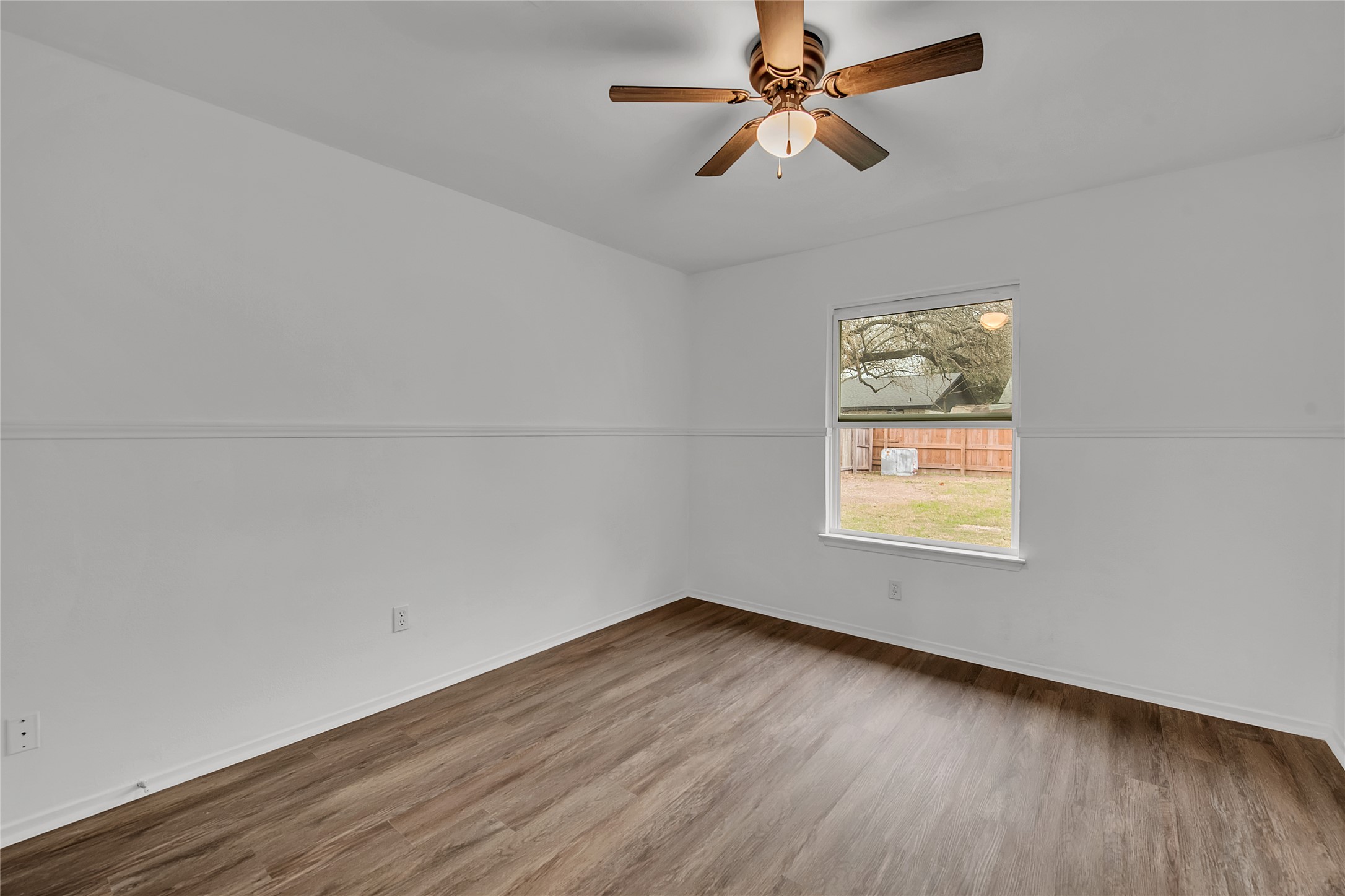 7209 Gunnison Pass Austin, TX 78724 - Photo 17 of 19 A comfortable bedroom boasts wide plank flooring and a classic ceiling fan, with a window offering a private backyard view.