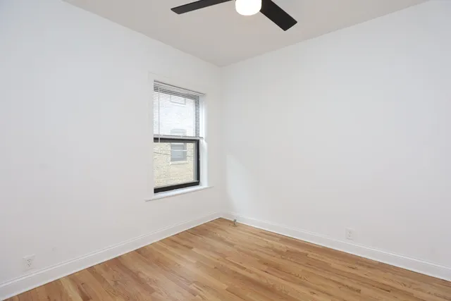 an empty room with wooden floor cabinet and windows