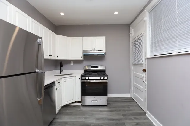 a kitchen with stainless steel appliances a refrigerator stove and white cabinets