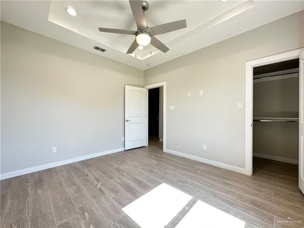 an empty room with wooden floor and a ceiling fan