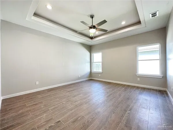 an empty room with wooden floor fan and windows