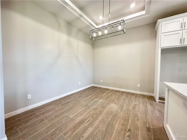a view of an empty room with wooden floor a ceiling fan and a window