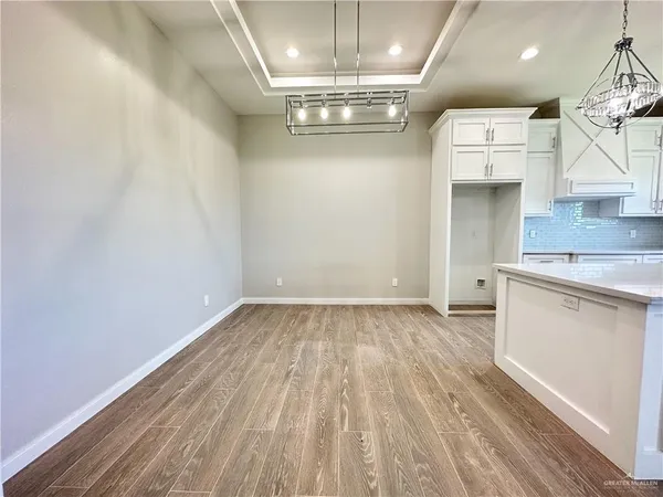 en empty room with wooden floor and kitchen view