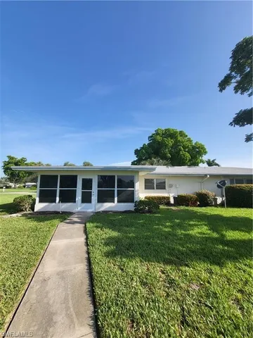 a front view of a house with a garden and trees