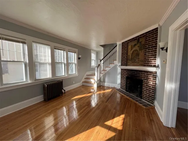 wooden floor in an empty room with a fireplace and windows