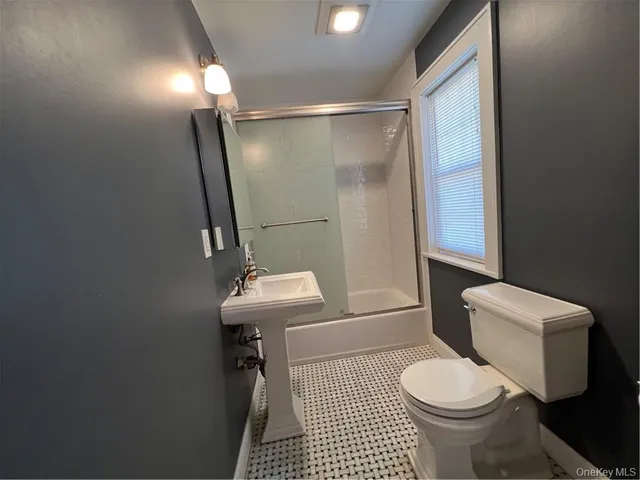 a bathroom with a sink a toilet a mirror and shower