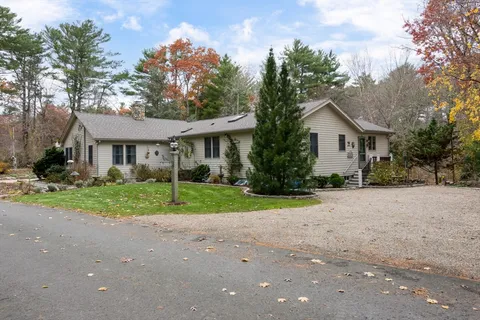 a view of a house with a yard and large trees