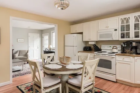 a kitchen with stainless steel appliances kitchen island granite countertop a dining table chairs and a refrigerator