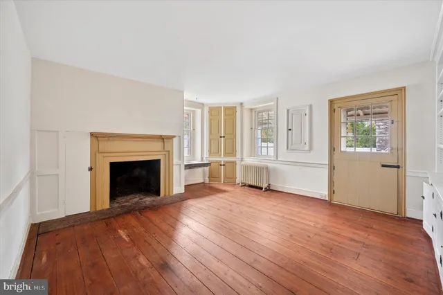 an empty room with windows and fireplace
