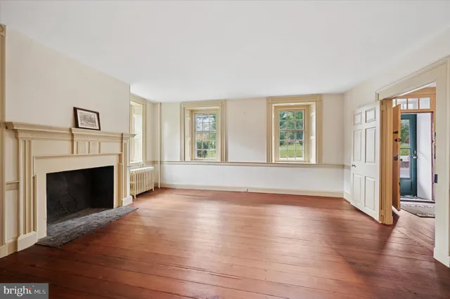 an empty room with windows fireplace and wooden floor