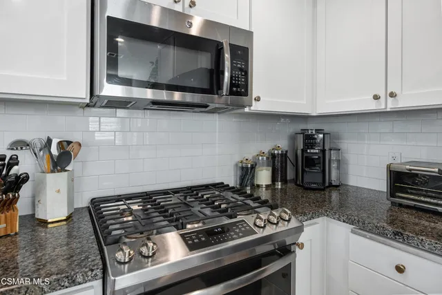 a kitchen with granite countertop a stove and a microwave