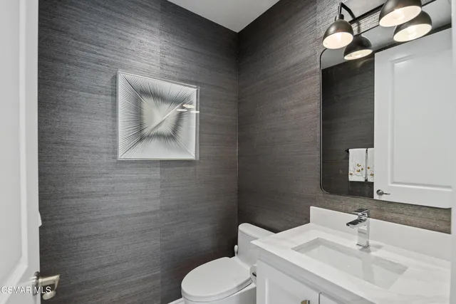 a bathroom with a toilet sink vanity and mirror