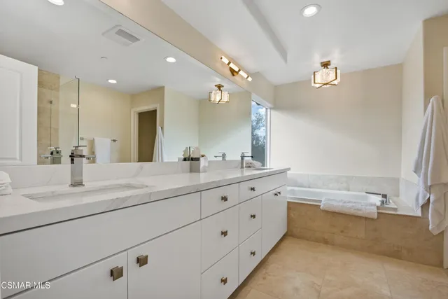 a bathroom with a granite countertop sink mirror and a bath tub
