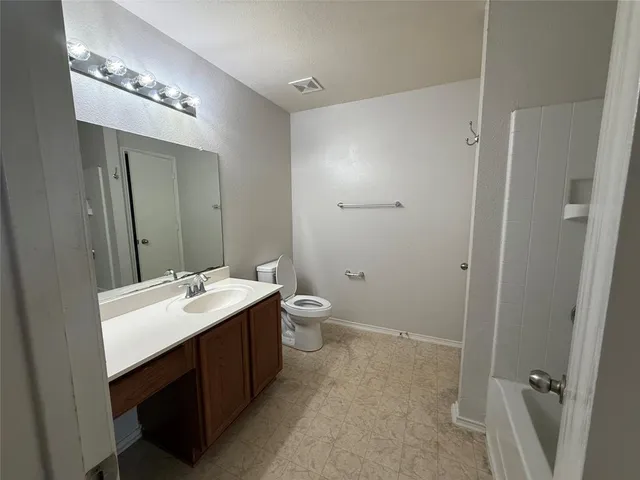 a spacious bathroom with a double vanity sink toilet and mirror