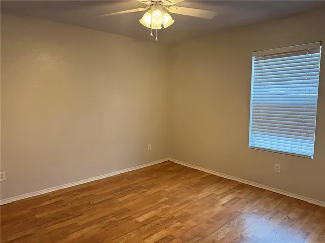 a view of a room with wooden floor and a chandelier fan