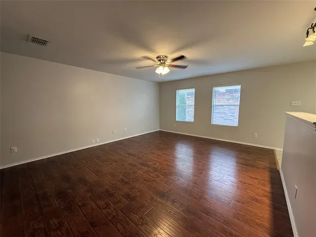 a view of an empty room with window and wooden floor