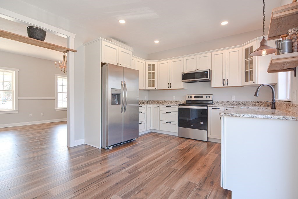 260 Main Street, Unit 3 Blackstone, MA 01504 - Photo 3 of 40 a kitchen with stainless steel appliances granite countertop a refrigerator a stove top oven a sink and dishwasher with wooden floor