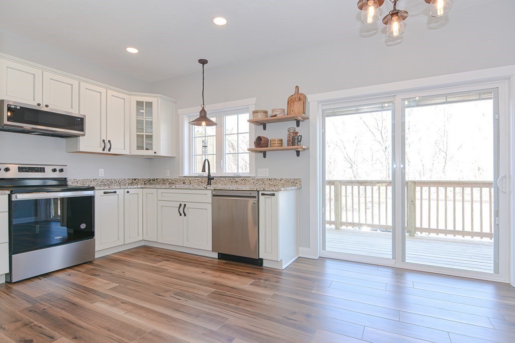 260 Main Street, Unit 3 Blackstone, MA 01504 - Photo 4 of 40 a kitchen with stainless steel appliances granite countertop a stove a sink and white cabinets with wooden floors