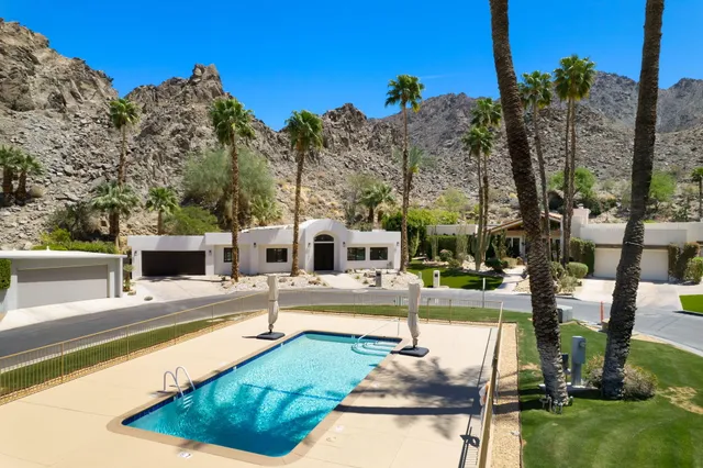 a front view of a building with a garden and trees