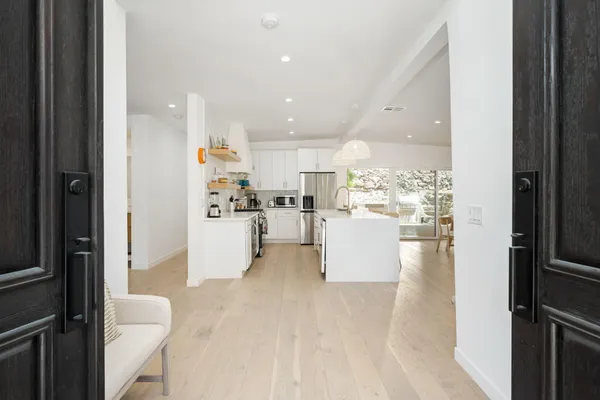 a view of open kitchen with white cabinets and refrigerator