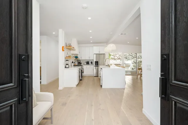 a view of open kitchen with white cabinets and refrigerator
