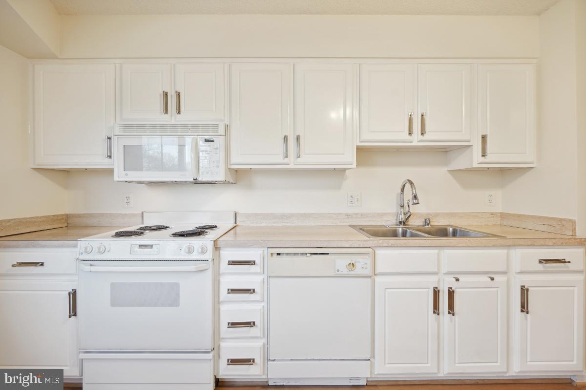 14801 Pennfield Circle, Unit 401 Silver Spring, MD 20906 - Photo 13 of 31 a kitchen with granite countertop white cabinets and white appliances