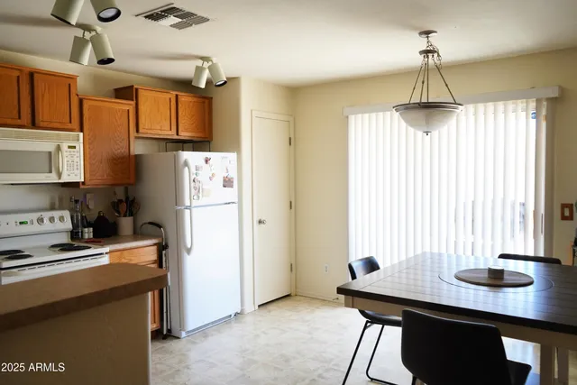 a kitchen with stainless steel appliances a dining table chairs and a refrigerator