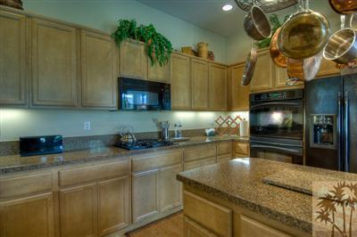 81249 Red Rock Road La Quinta, CA 92253 - Photo 7 of 25 a kitchen with stainless steel appliances granite countertop a sink a stove cabinets and a wooden floor